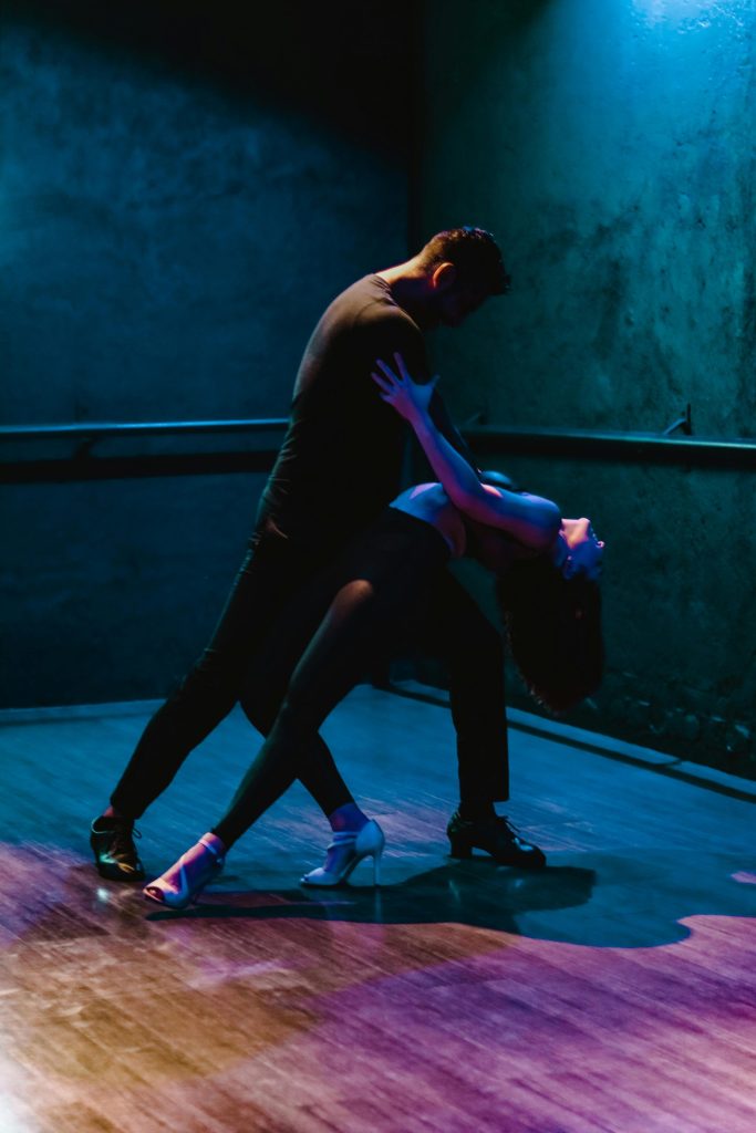 A couple performing a passionate salsa dance in a dimly lit studio in Ciudad de México.
