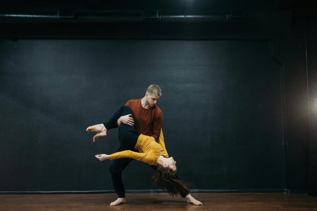 A couple performing an expressive dance move in a studio setting.